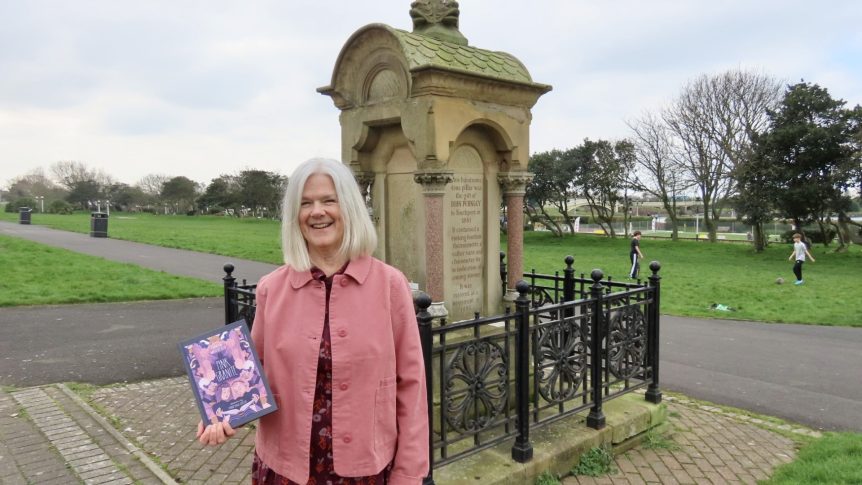 Carran Waterfield, author of Pink Granite holding book near memorial made of pink granite